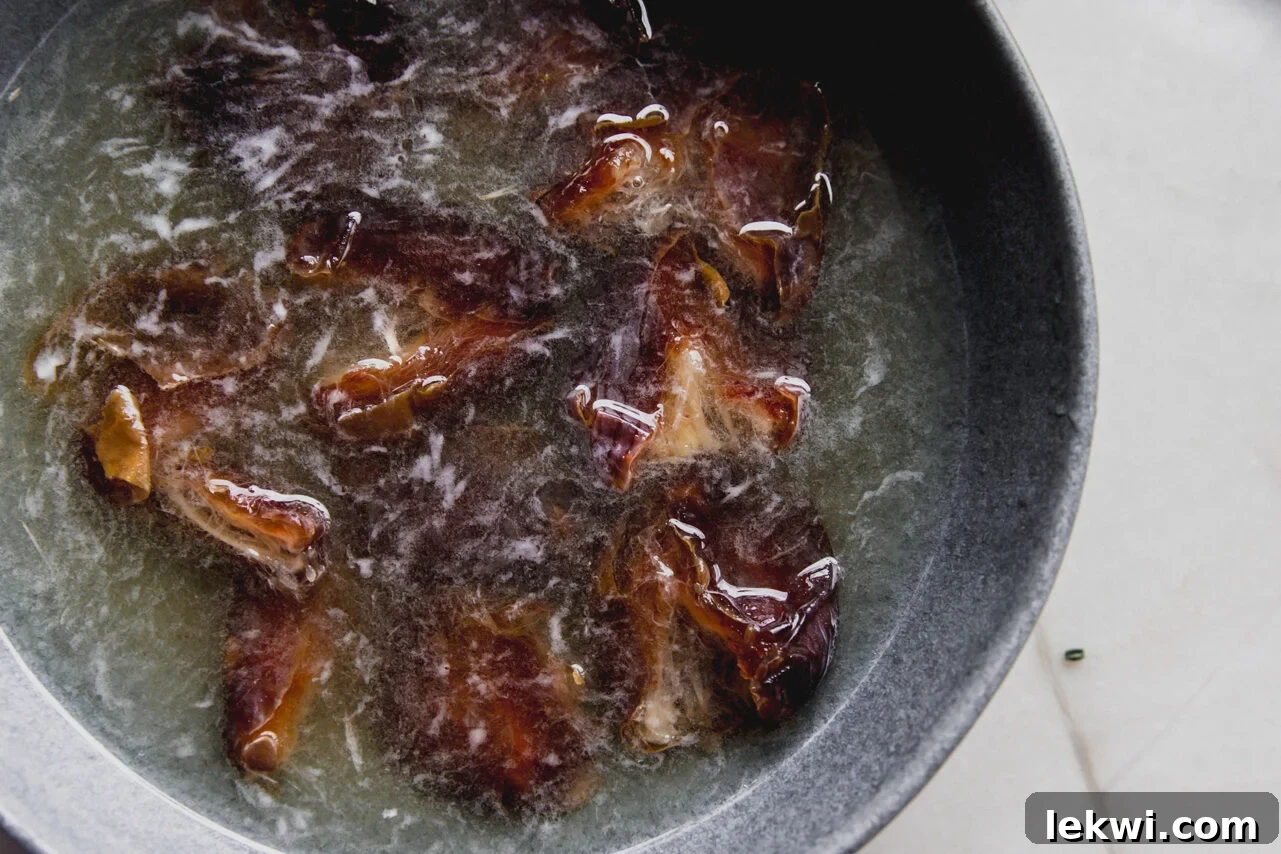 A bowl of fresh dates soaking in hot water to soften them for the filling.