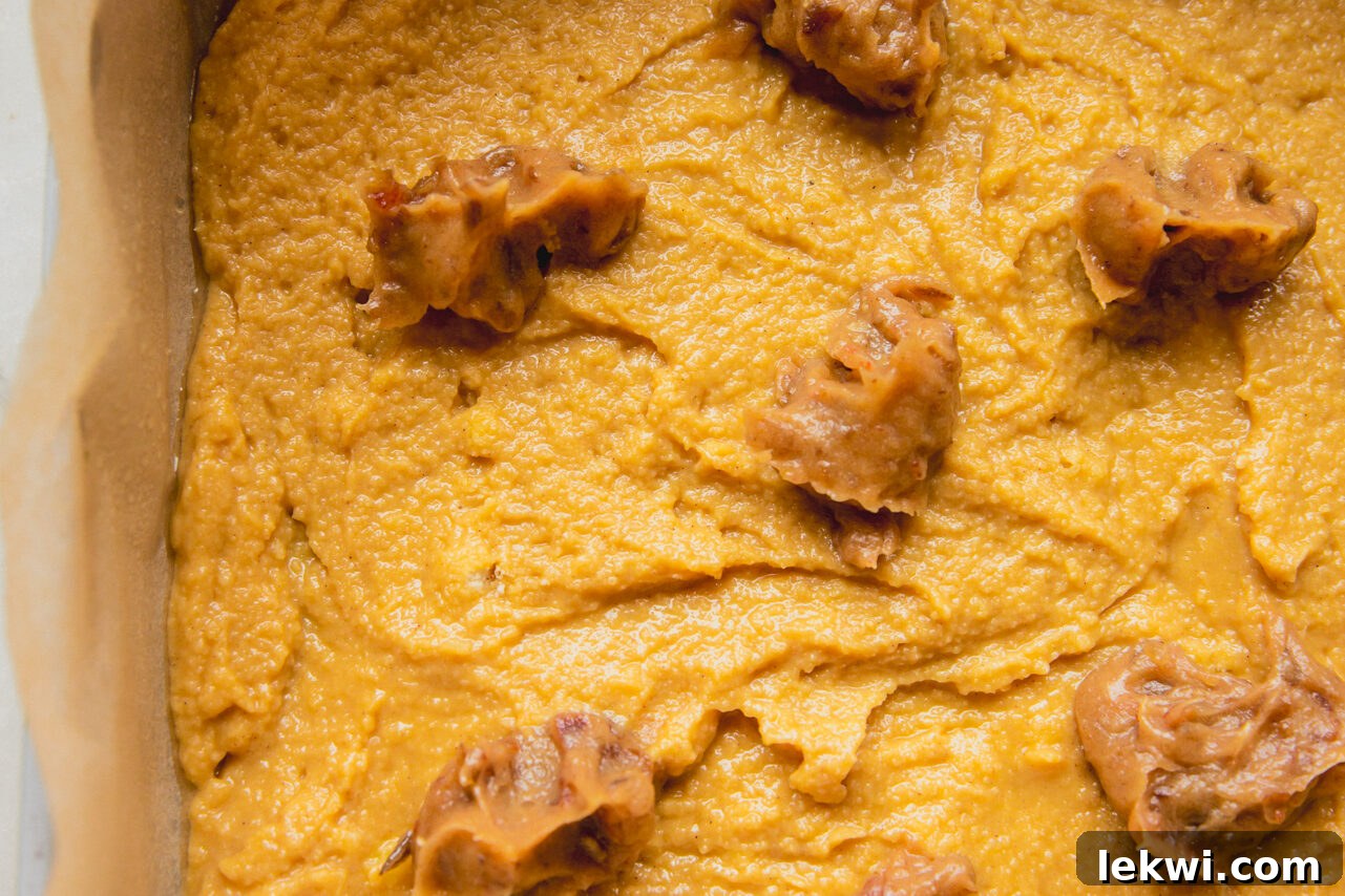 A baking dish with half the cake batter, topped with small, evenly spaced spoonfuls of the date mixture.