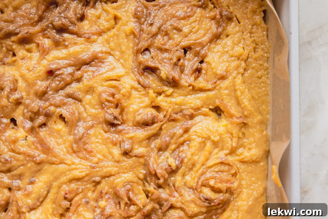 The full cinnamon roll cake batter in the baking pan, topped with the second layer of date swirl, ready for the oven.