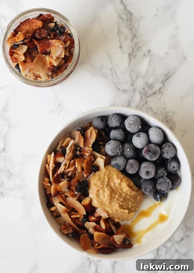 A vibrant breakfast bowl topped with Grain Free Blueberry Coconut Granola (Paleo & AIP)