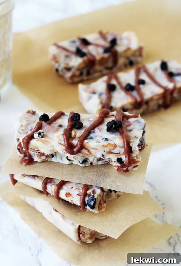 Several homemade grain-free granola bars stacked neatly with parchment paper in between, ready for a healthy snack.