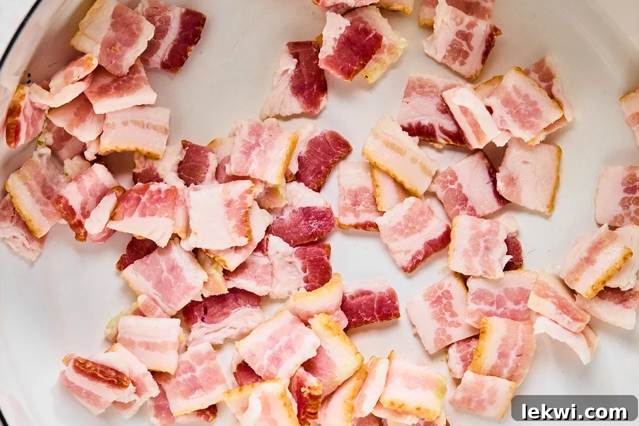 Crispy bacon sizzling in a hot pan on the stove, releasing its delicious aroma and fat.