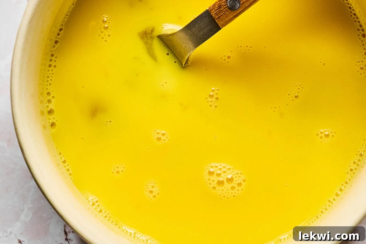 A bowl containing four eggs vigorously whisked with a tablespoon of water, ready to be added to the soup.
