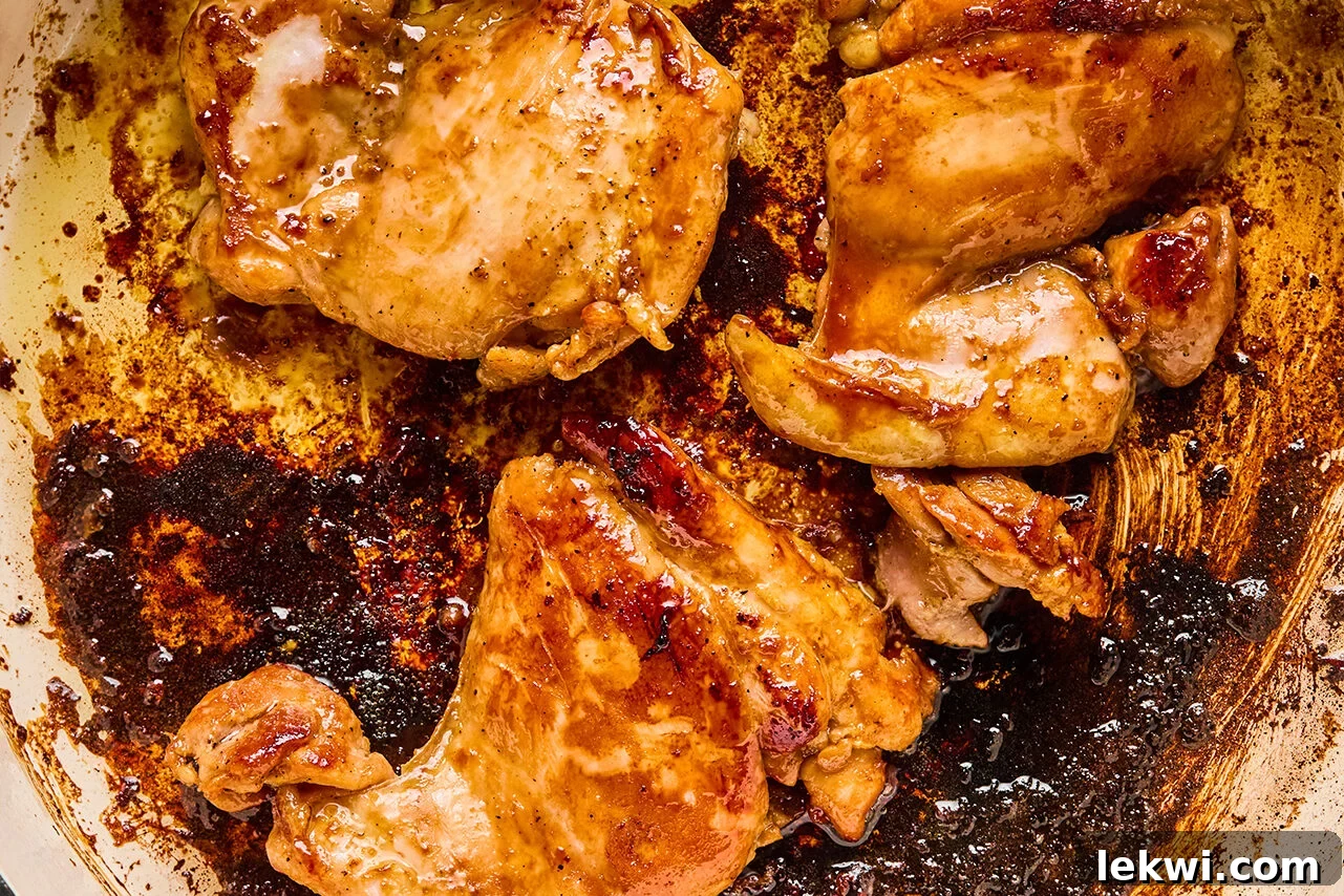 Chicken cooking in a pan on the stove, sizzling to a golden brown.