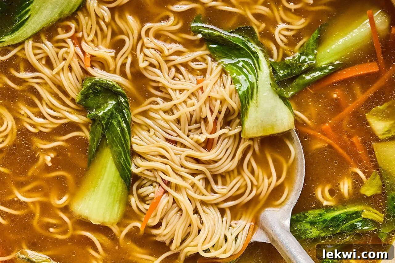Cooked ramen noodles in the broth with bok choy and carrots, ready for serving.