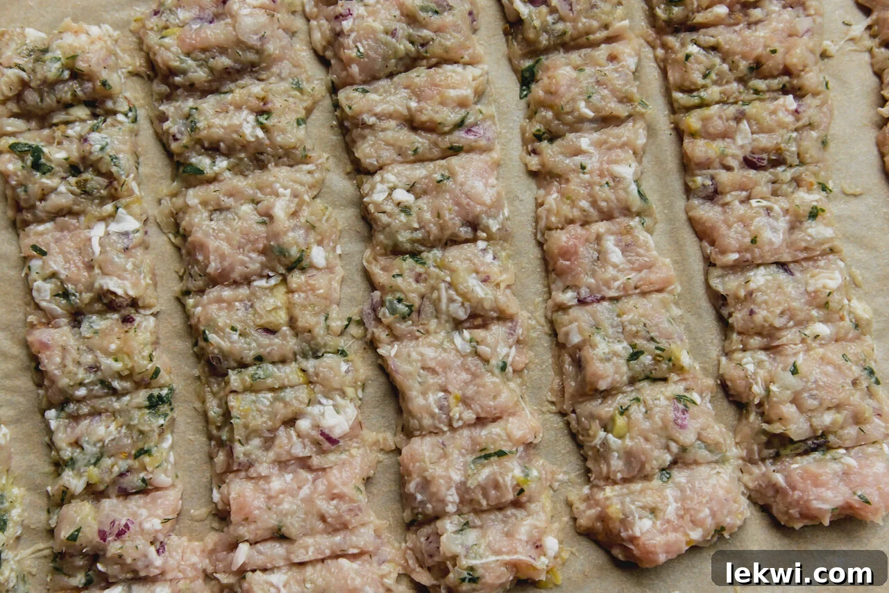 The chicken mixture pressed into an even layer on a baking sheet with scoring to mimic a kebab, ready for baking.