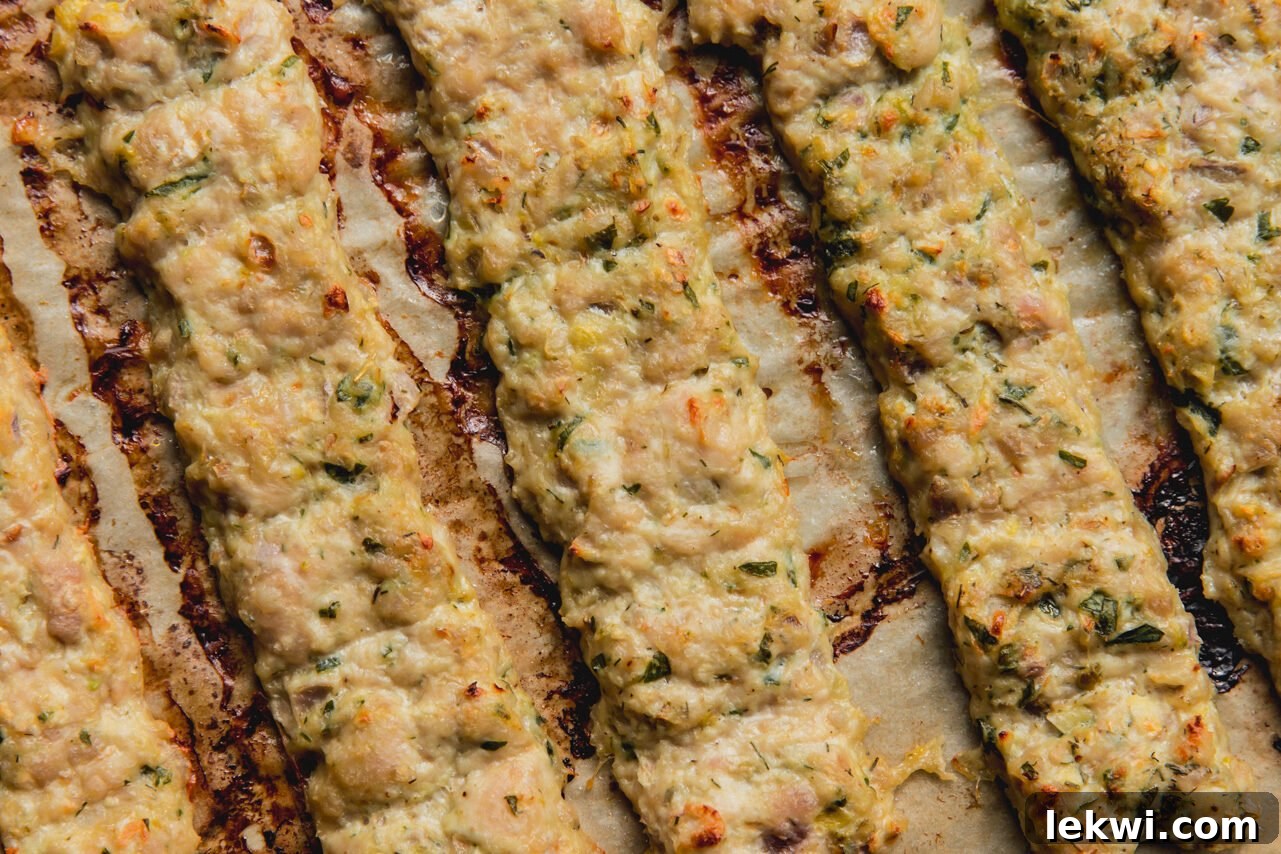 The ground chicken kebabs on a baking sheet, golden brown and cooked, after being baked.
