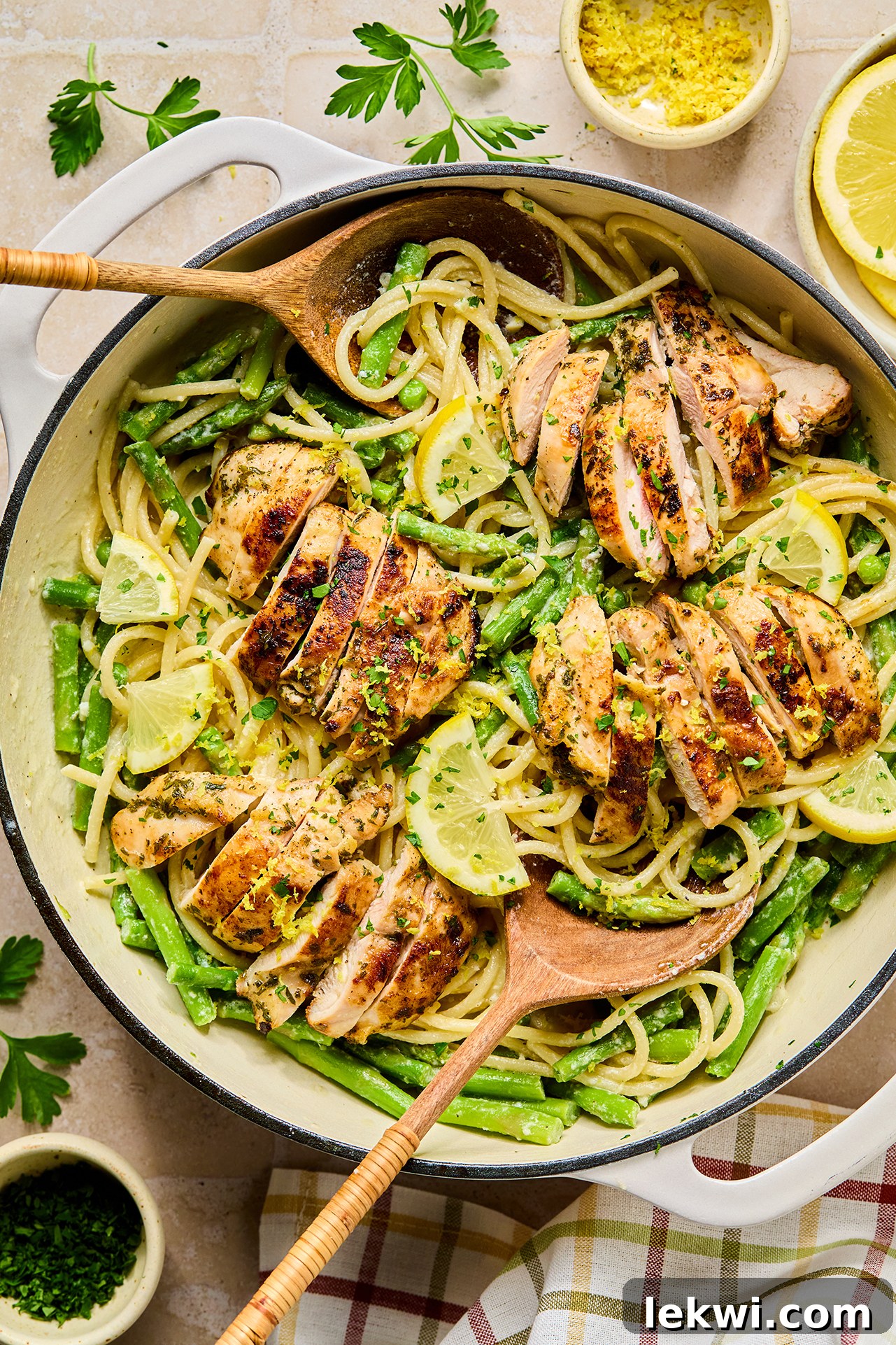 A large pot of freshly cooked lemon goat cheese pasta, steaming and ready to be served, with a wooden serving spoon dipped into it.