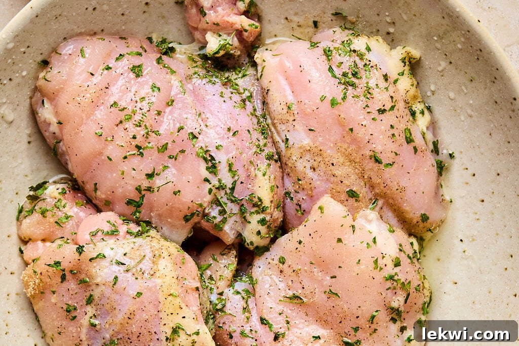 A bowl with raw chicken covered in seasoning and lemon juice marinating, ready for cooking.