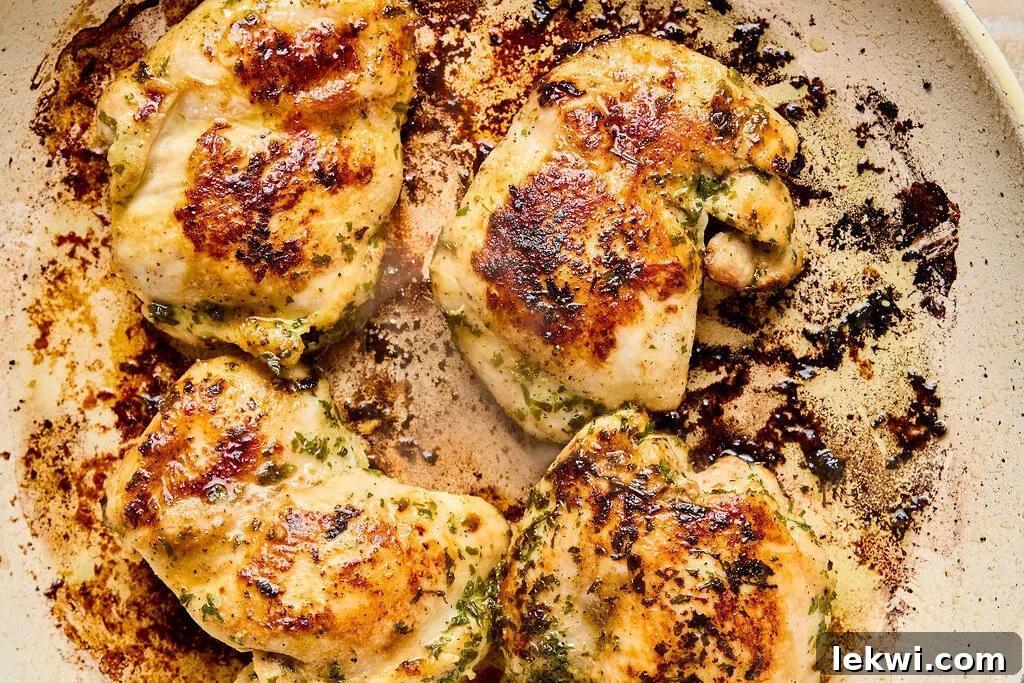 Chicken searing in a hot pan, developing a golden-brown crust.