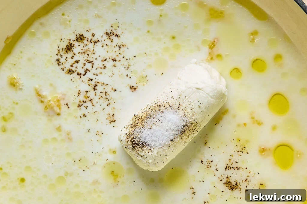 A pan with ghee, minced garlic, goat cheese, lemon juice, and almond milk cooking to create the creamy sauce.