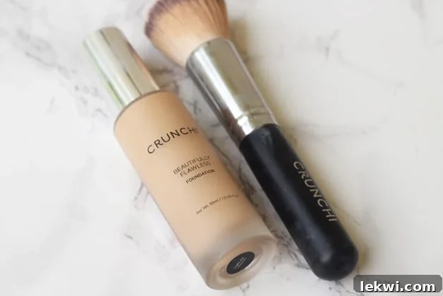 A bottle of foundation and a brush lying next to each other on a counter.