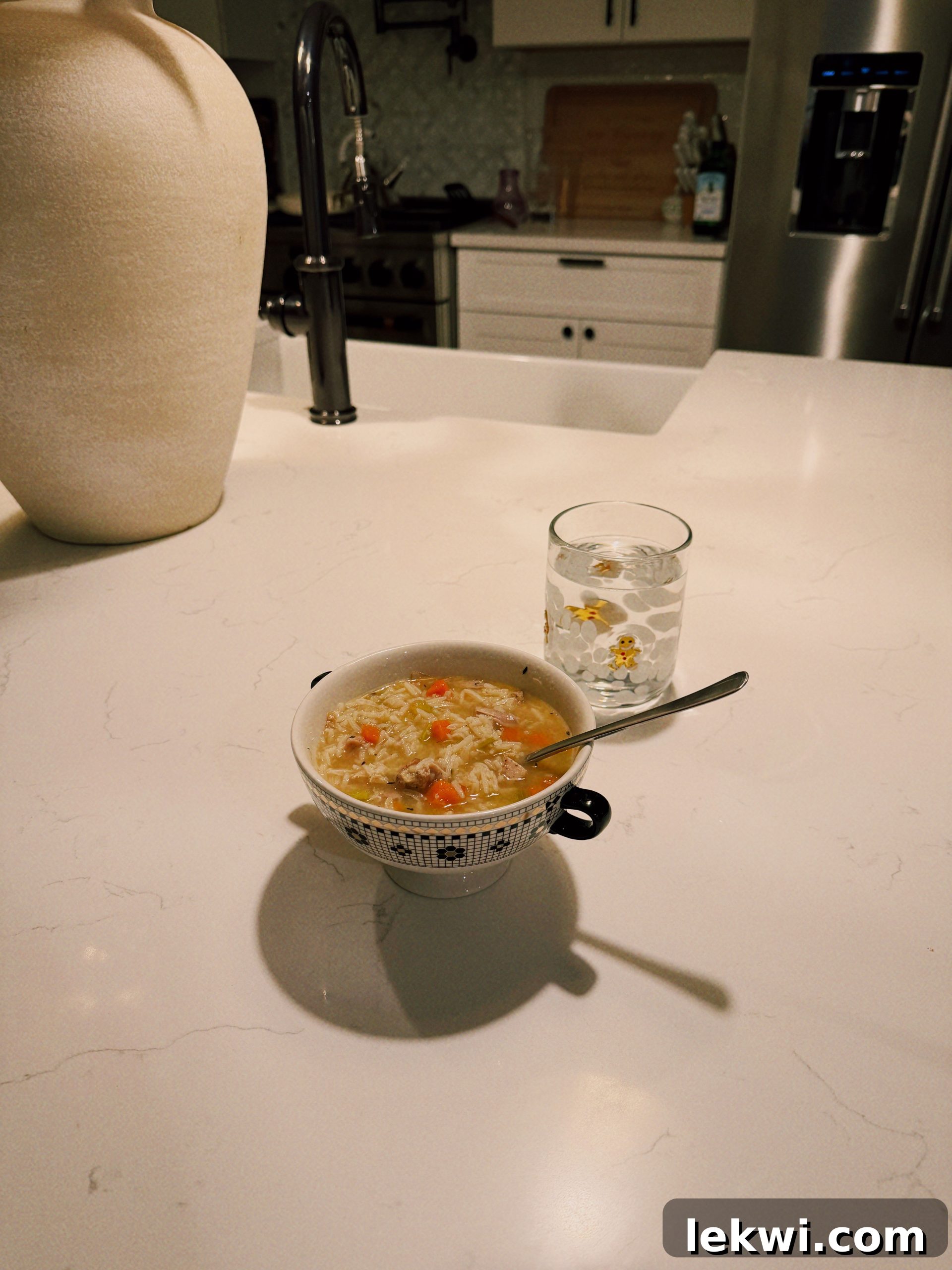A vibrant bowl of chicken and wild rice soup from Spring Bone Kitchen, garnished with fresh herbs.