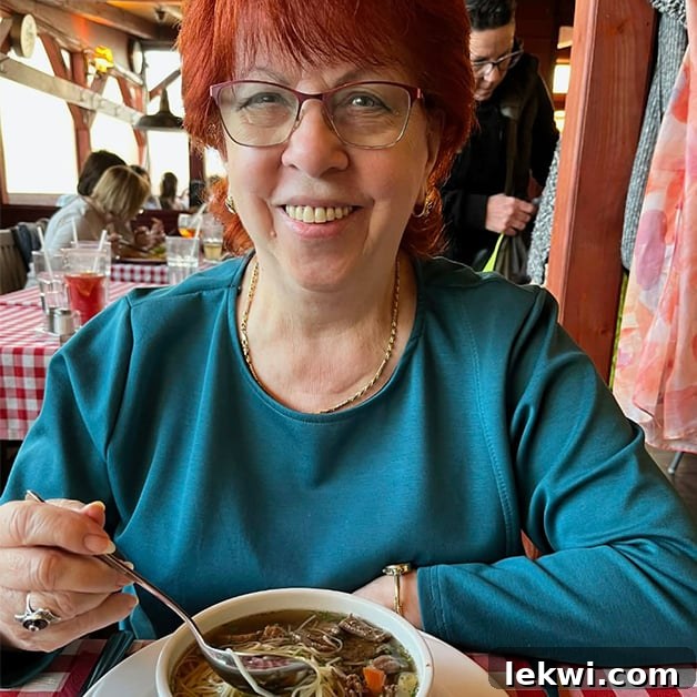 A vibrant woman with red hair and a blue shirt joyfully eating a bowl of soup, symbolizing health, tradition, and radiant living.