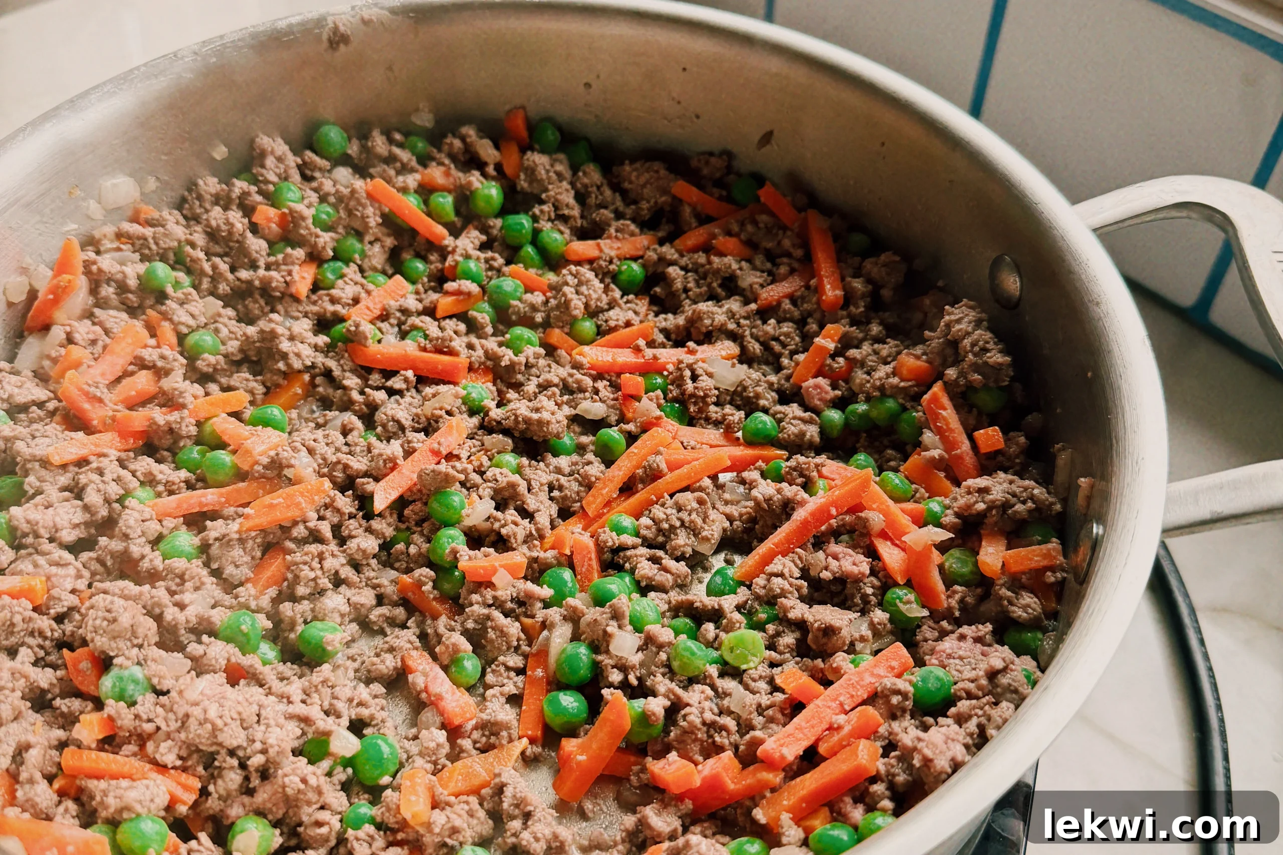 Comforting Gluten-Free Beef Pot Pie 4 A saute pan filled with browned ground beef, onions, and mixed vegetables, actively cooking.