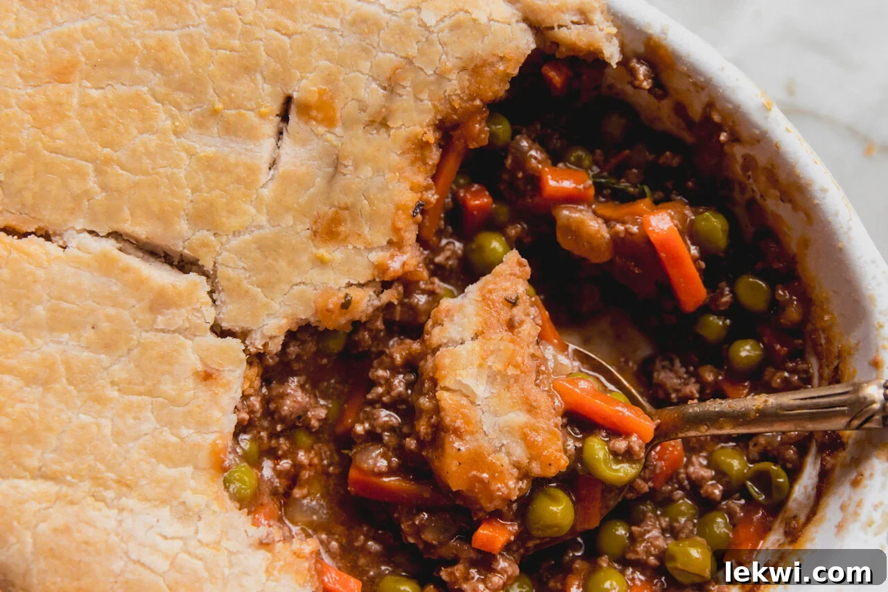 Comforting Gluten-Free Beef Pot Pie 9 A close-up of a serving of gluten-free beef pot pie being scooped out of the baking dish, revealing the rich filling and flaky crust.