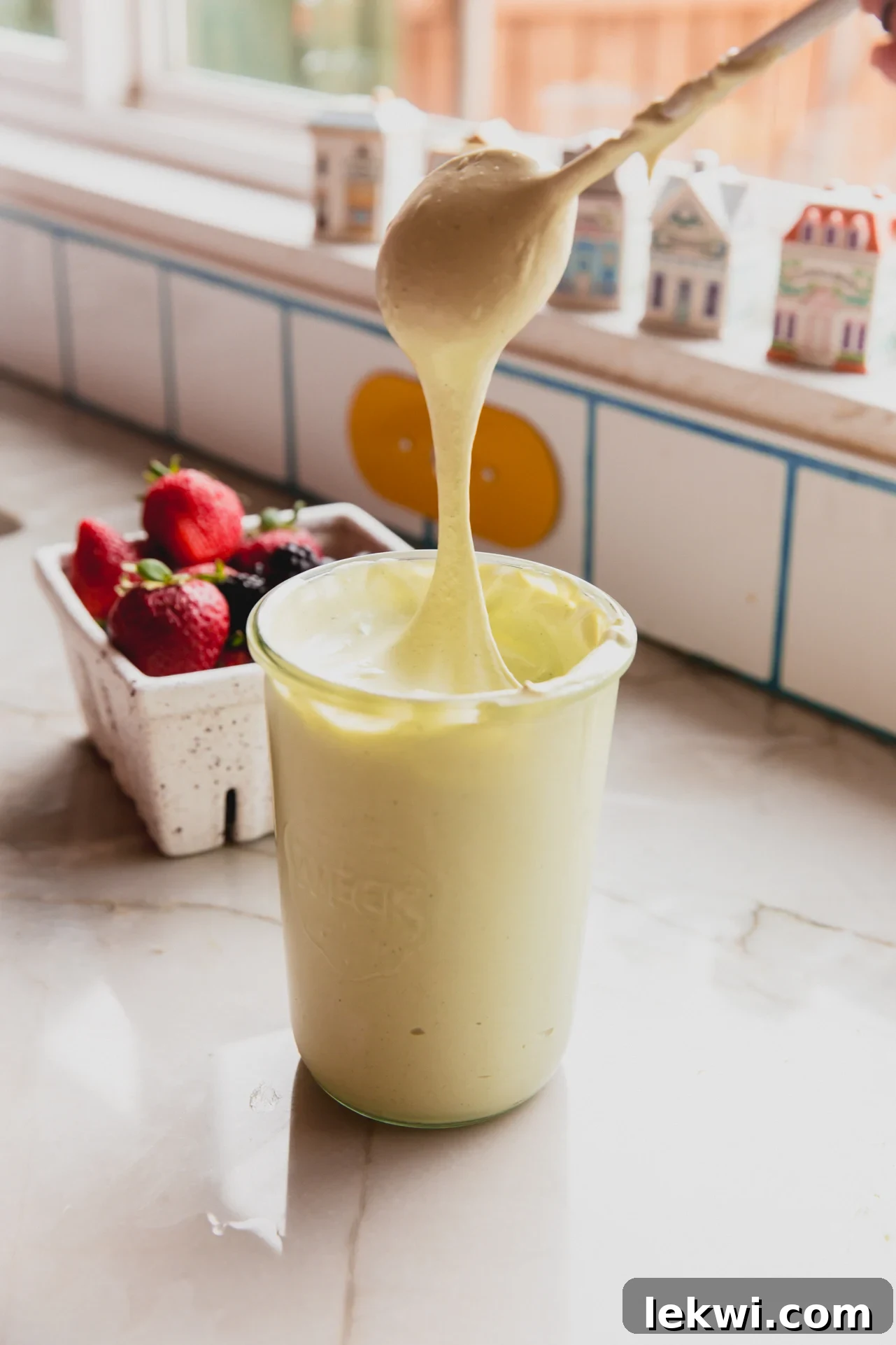 Matcha Mallow Clouds 2 A jar of fluffy matcha marshmallow fluff with a spoon dipping in, scooping up the vibrant green cream.
