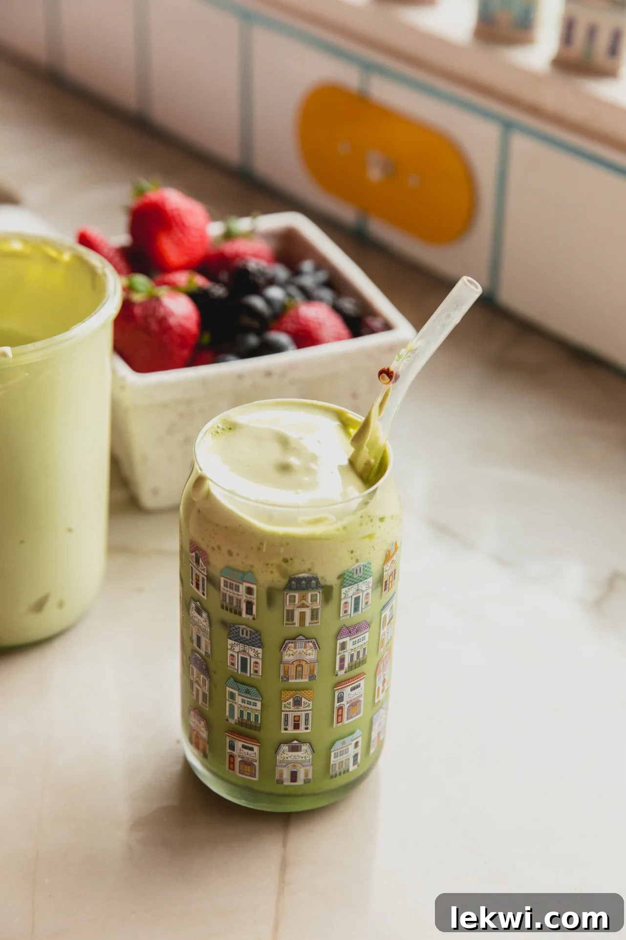 Matcha Mallow Clouds 4 An iced matcha latte topped generously with matcha marshmallow fluff, with fresh strawberries in the blurred background.