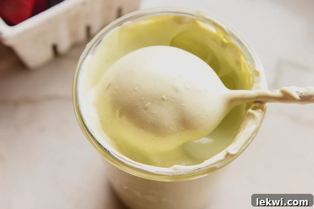 Matcha Mallow Clouds 6 A beautiful glass jar filled with vibrant green matcha marshmallow fluff, with a spoon scooping a portion out.