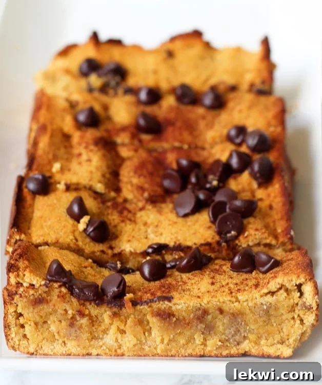 A perfectly baked loaf of Paleo Chocolate Chip Pumpkin Bread, sliced and ready to serve, adorned with a scattering of dairy-free chocolate chips.