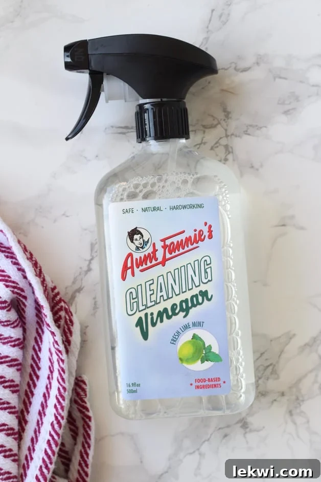 A shot of Aunt Fannie\'s Cleaning Vinegar in a spray bottle with a cleaning cloth next to it, ready for action.