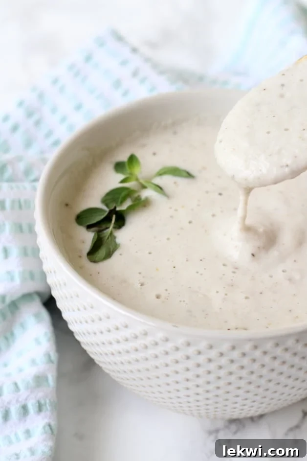 A bowl of garlic cream sauce with a spoon taking a spoonful out.