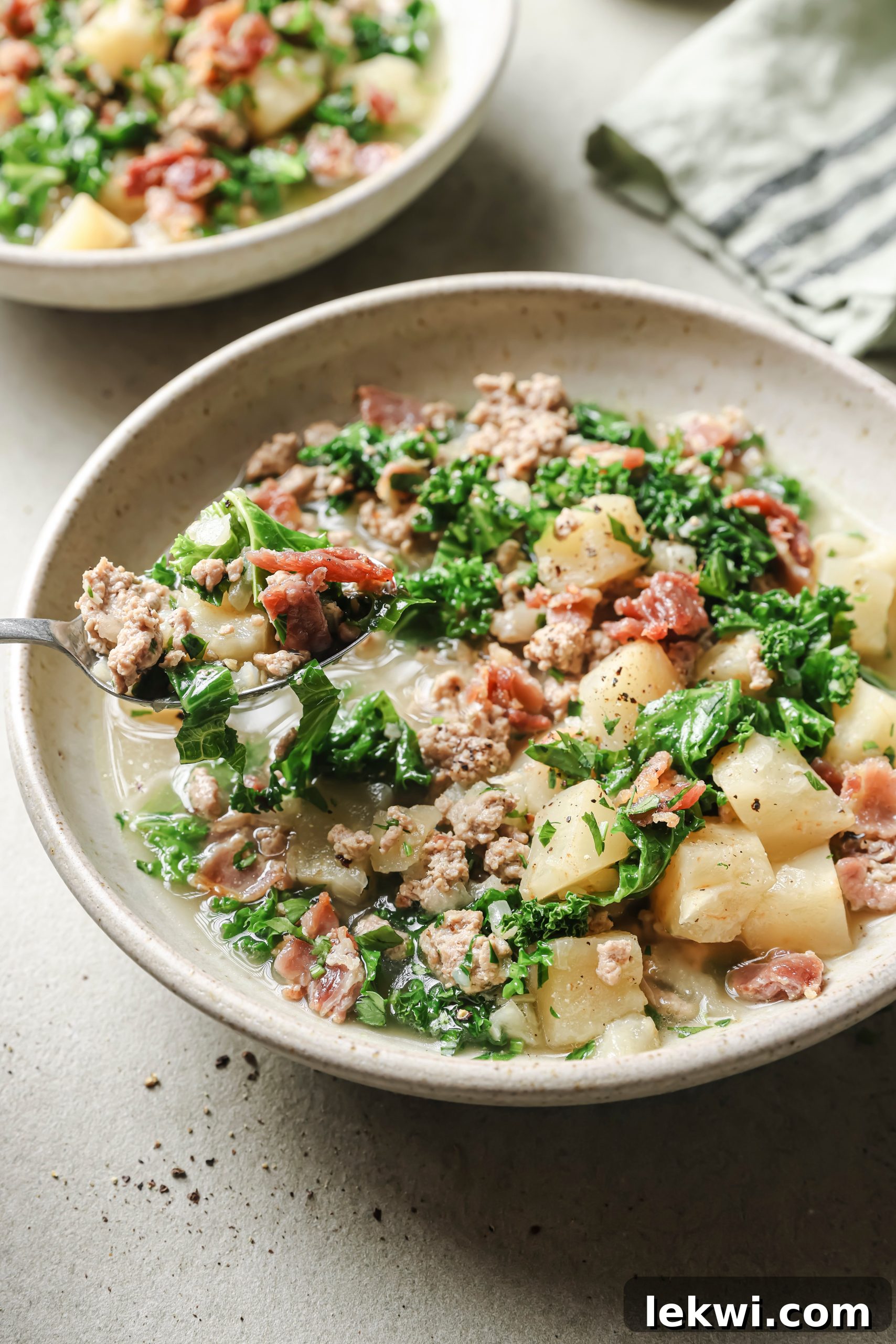 A beautifully presented bowl of Zuppa Toscana, ready to be enjoyed, garnished with bacon and parsley.