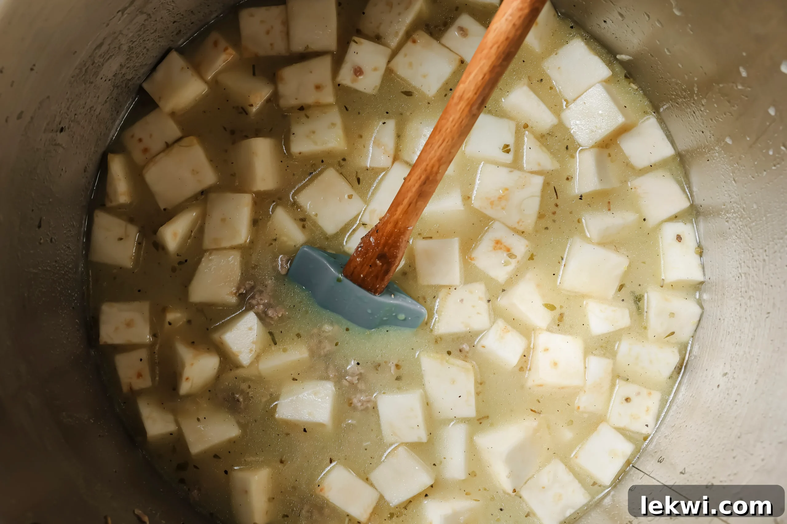 Chicken broth, coconut milk, diced sweet potatoes, salt, and pepper added to the Instant Pot with the cooked sausage and aromatics.