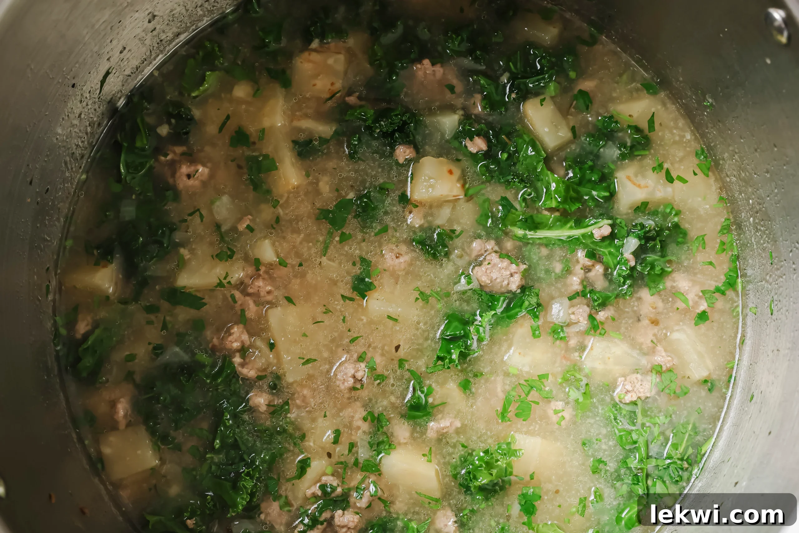 Fresh kale added to the hot Zuppa Toscana in the Instant Pot, wilting into the soup.