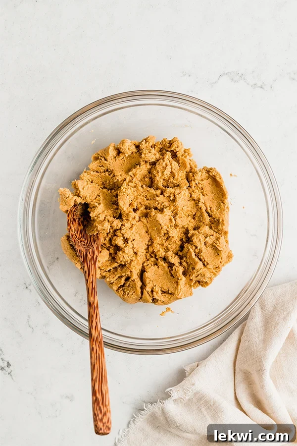 A bowl with pumpkin pie donut hole batter and a wooden mixing spoon.