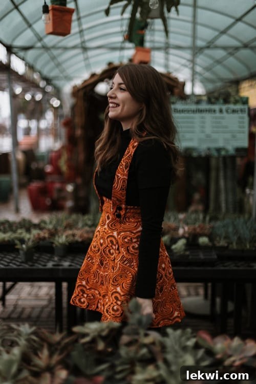 A photo of Michelle in a red printed dress over a black top standing in a market.