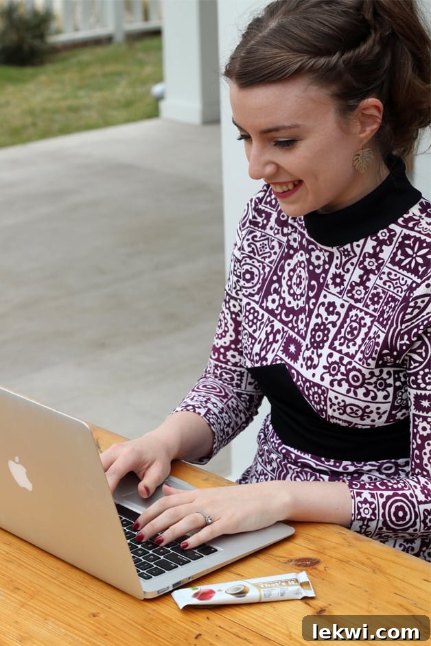 Michelle sitting in a purple and white dress typing at a computer.