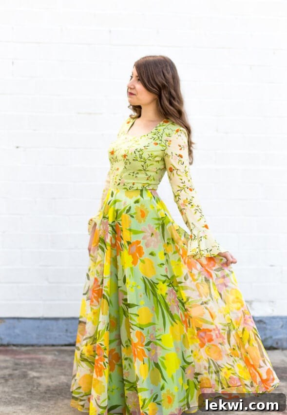 Michelle in a vibrant printed 1970s maxi dress against a white concrete background, showcasing unique vintage style.