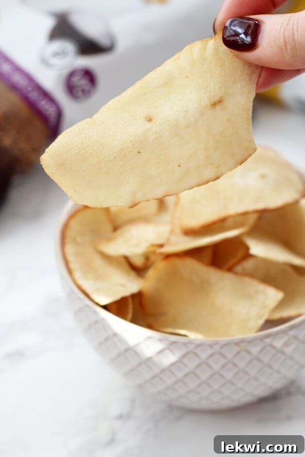 A crisp white bowl overflowing with golden Artisan Tropic cassava chips, perfectly salted.