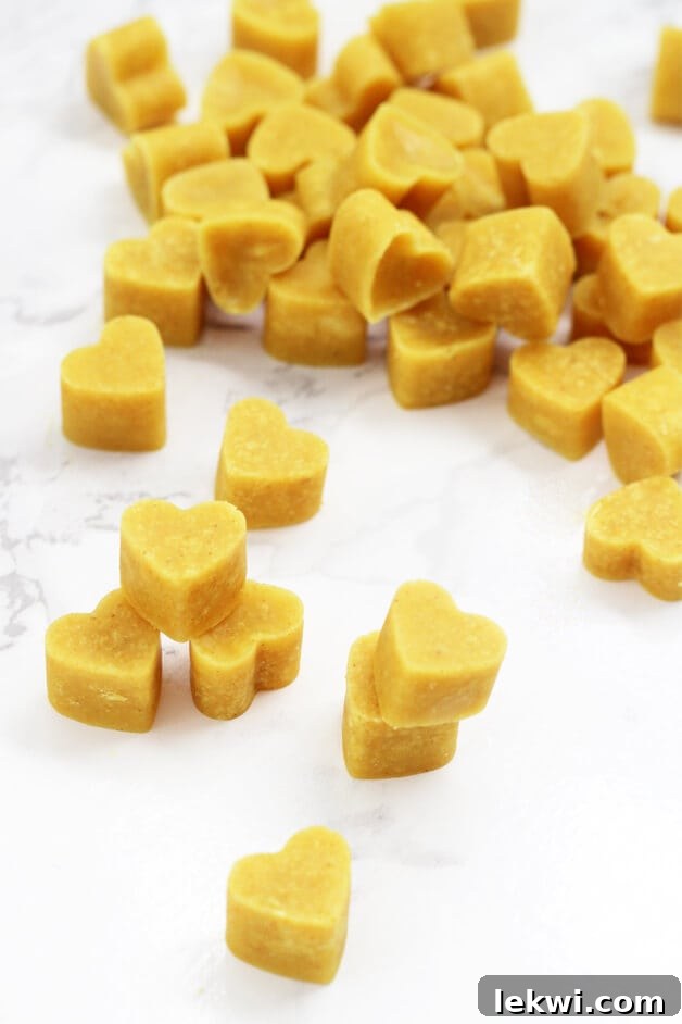A pile of heart-shaped turmeric chewables, vibrant yellow-orange in color.