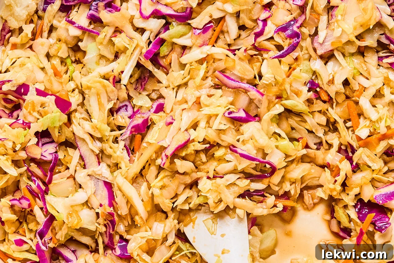 The coleslaw mix and coconut aminos added into the pan to saute with the onions, garlic, and ginger.