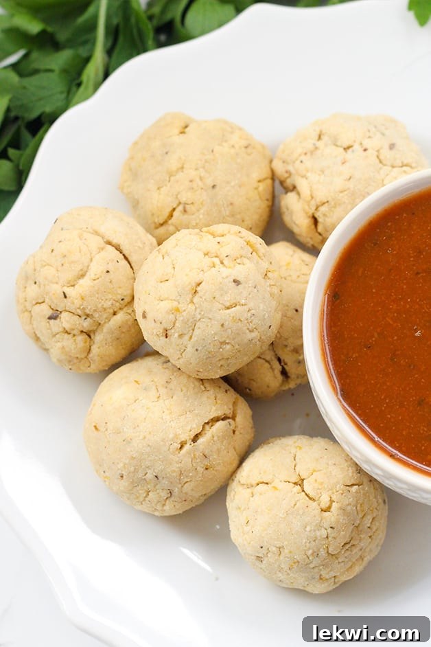 A white plate with pizza bites and a white bowl of dipping sauce.