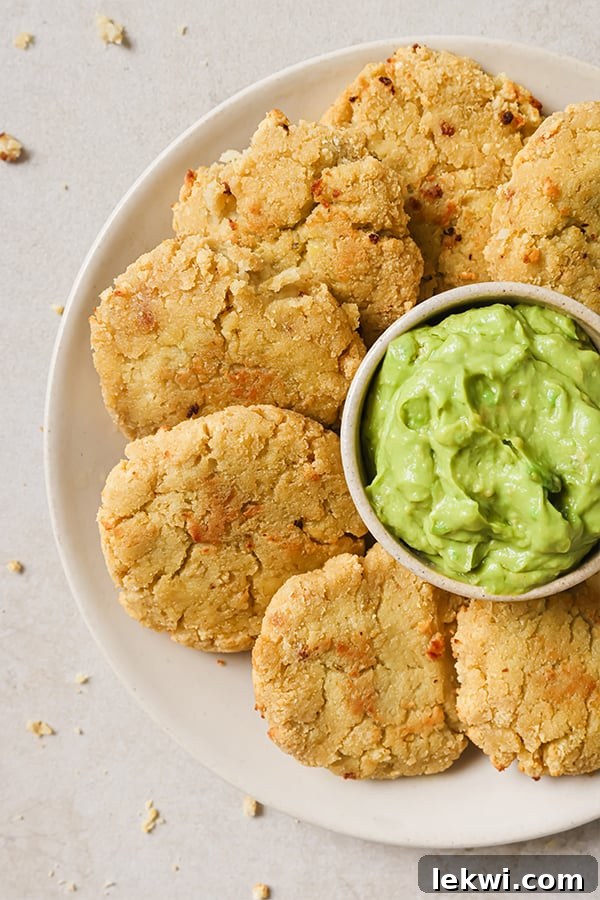 A vibrant close-up of cauliflower veggie nuggets arranged around a small bowl of fresh guacamole, ready for dipping.