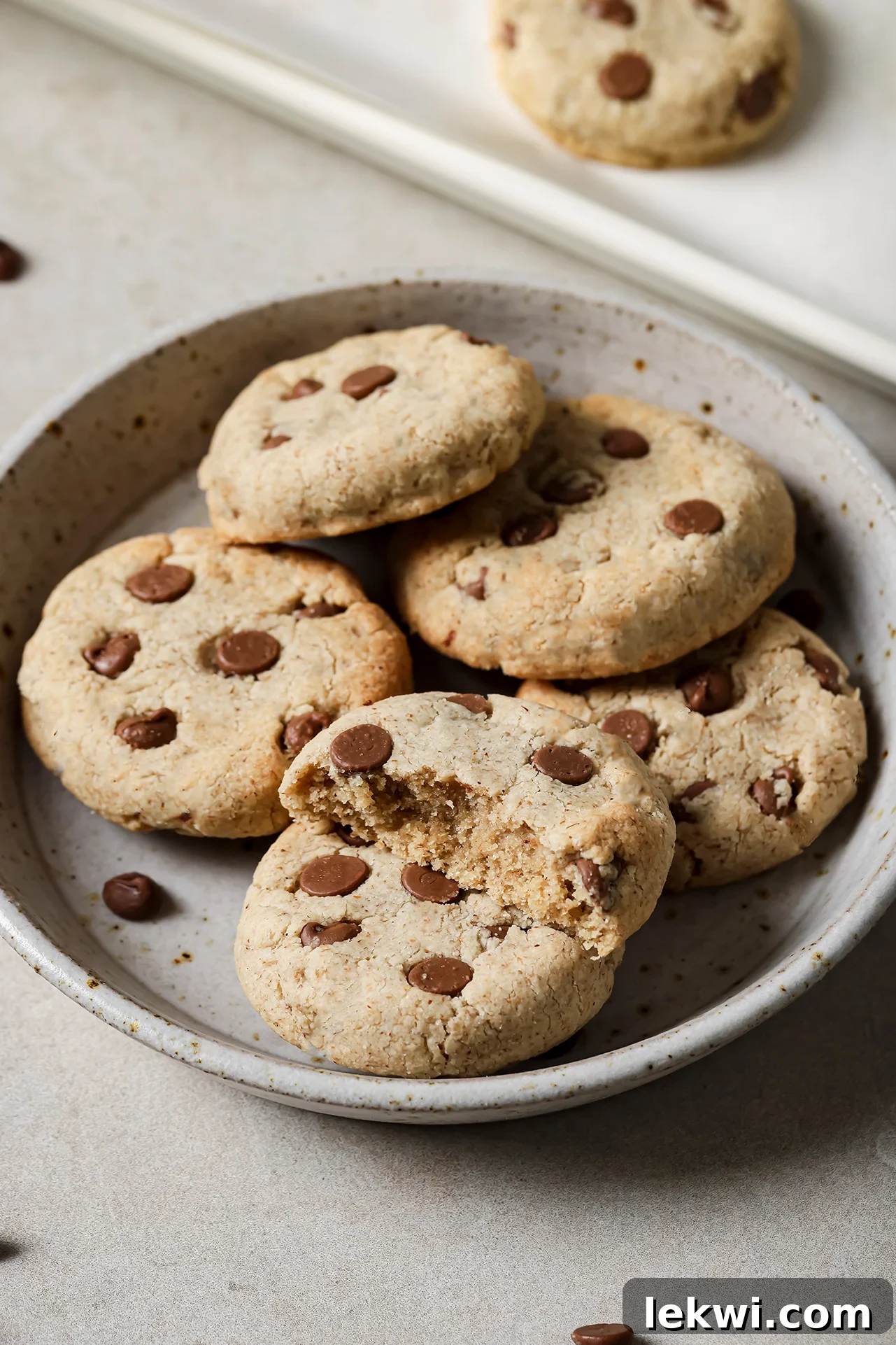 Three tigernut flour chocolate chip cookies neatly stacked on a small white plate, ready to be enjoyed.