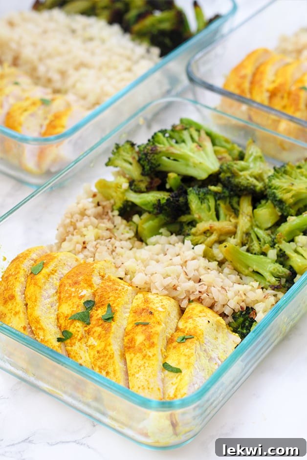 A glass meal prep container filled with turmeric chicken, cauliflower rice, and roasted broccoli.