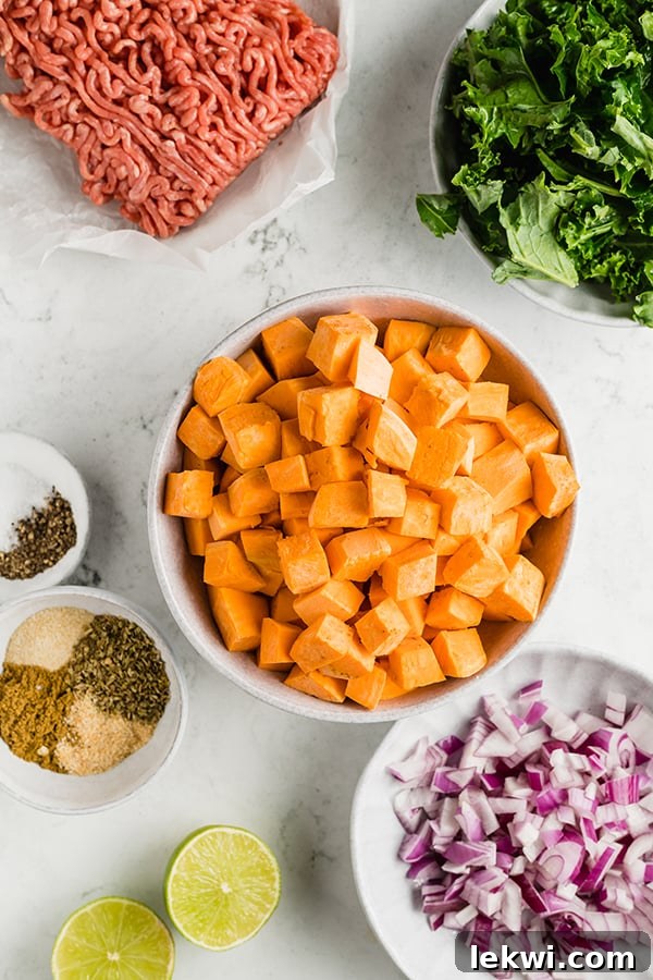 Fresh ingredients laid out: sweet potatoes, red onion, and kale for the skillet.