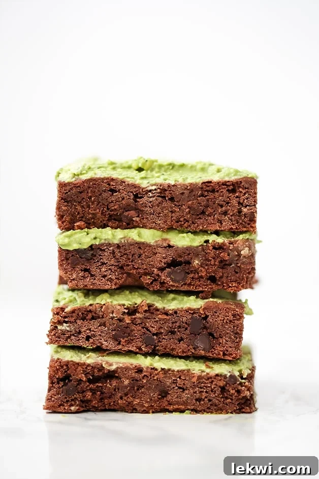 A stack of four AIP Paleo Matcha Brownies stacked on top of each other with green frosting.