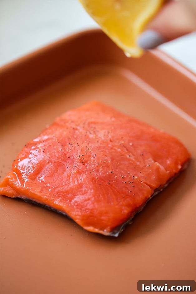 A sheet pan with a fillet of sockeye salmon on it, seasoned and ready for roasting.