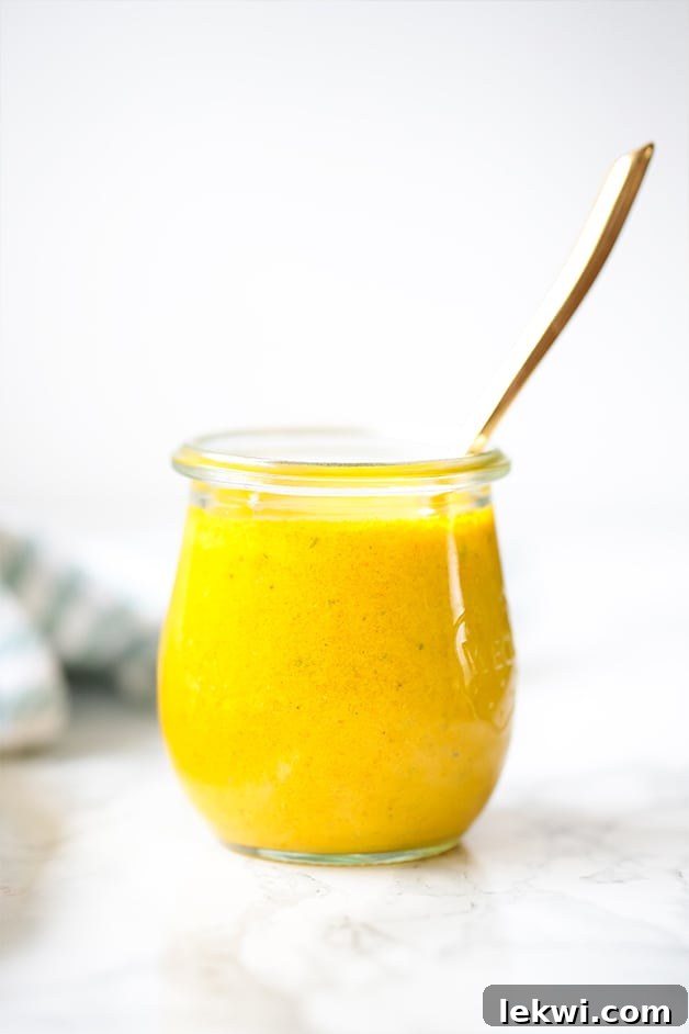 A glass jar filled with anti-inflammatory turmeric dressing and a spoon sticking out of it.