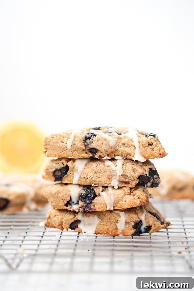 A perfectly stacked pile of four golden lemon blueberry scones on a metal cooling rack.