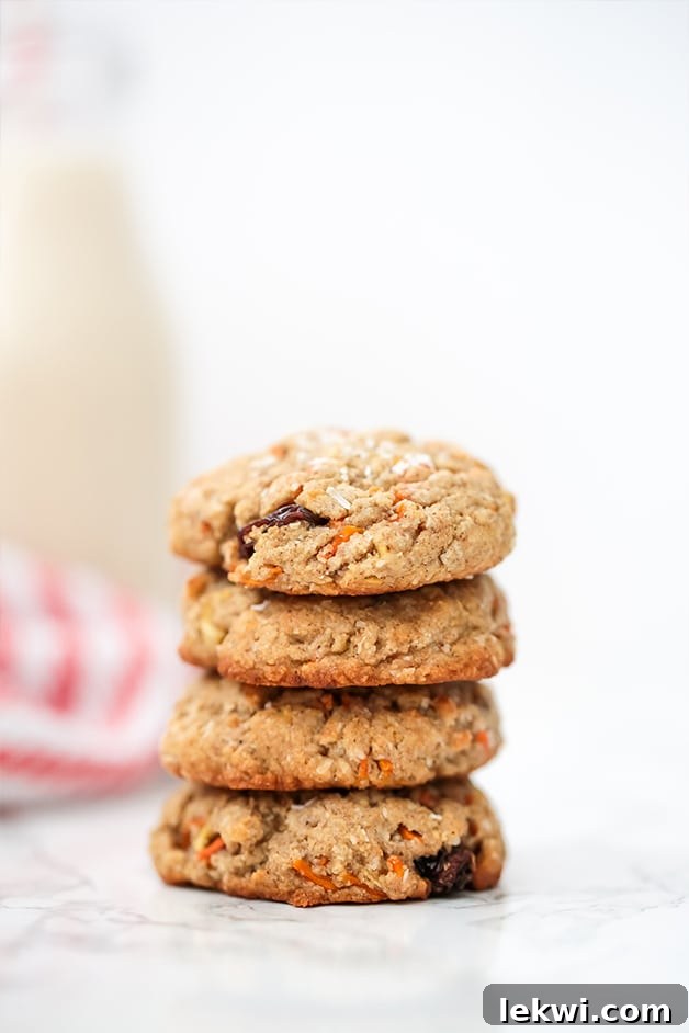 Several soft and chewy Paleo Carrot Cake Protein Cookies stacked on a rustic wooden surface.