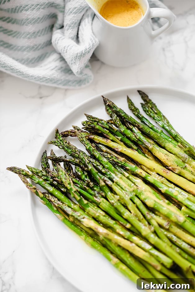 A beautifully arranged plate of freshly roasted asparagus spears, seasoned with turmeric dressing, ready to be enjoyed as a healthy AIP-compliant side dish.