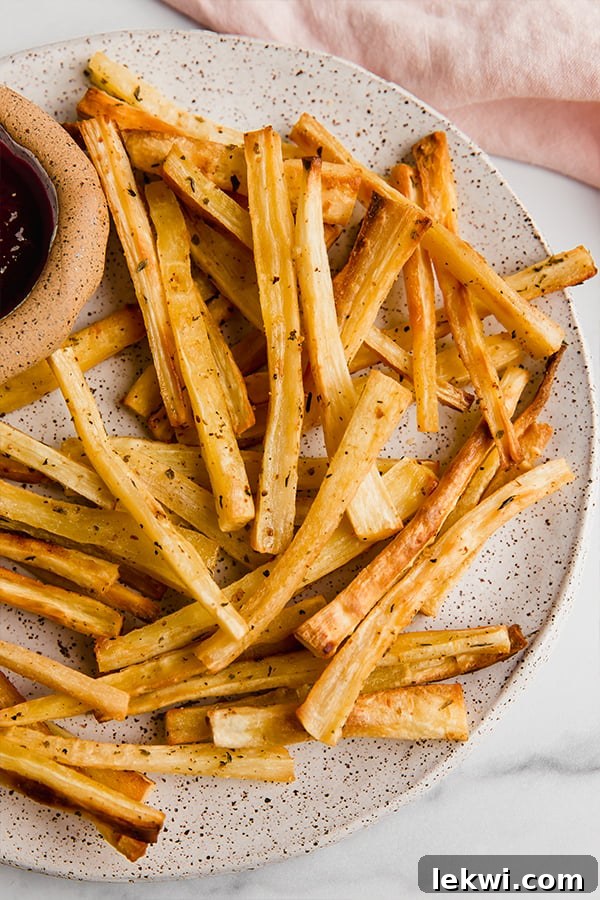 Parsnip fries on a plate with a dip on the side, ready to be enjoyed.