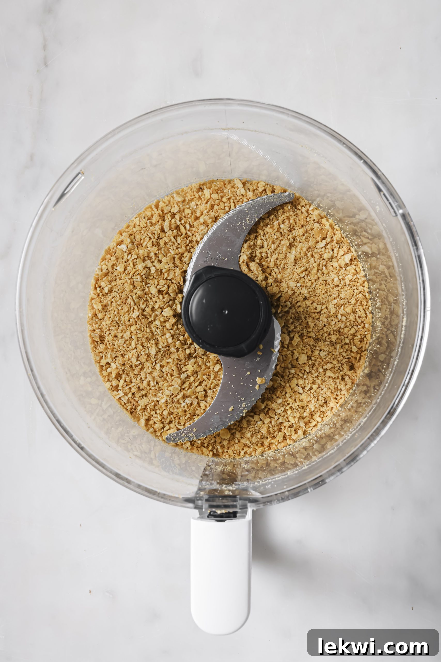 A food processor bowl filled with finely ground plantain chips, ready to become the crispy breading for the nuggets.