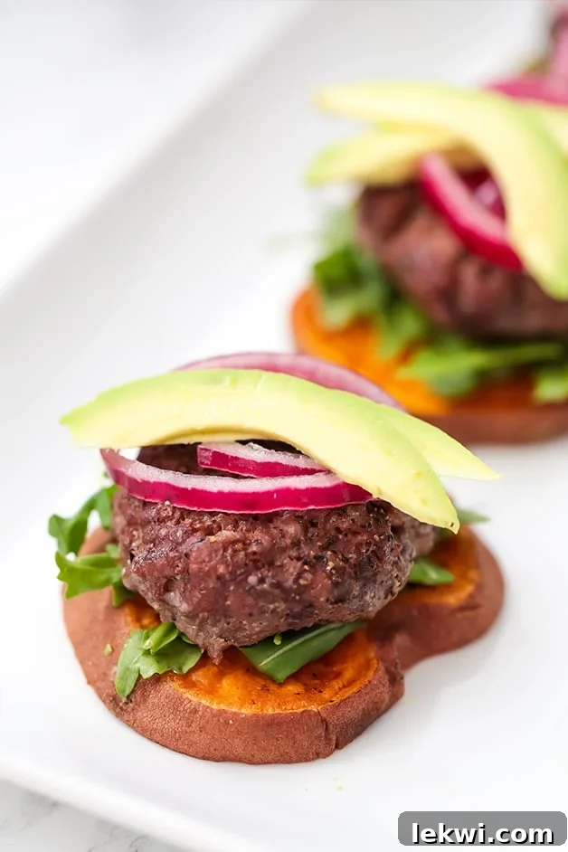 A plate with two sliders on sweet potato buns with onion and avocado on top.